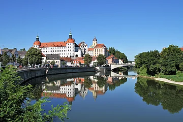 Stadtansicht mit Schloss und Brücke, Spiegelung im Fluss, blauer Himmel, Bäume am Ufer