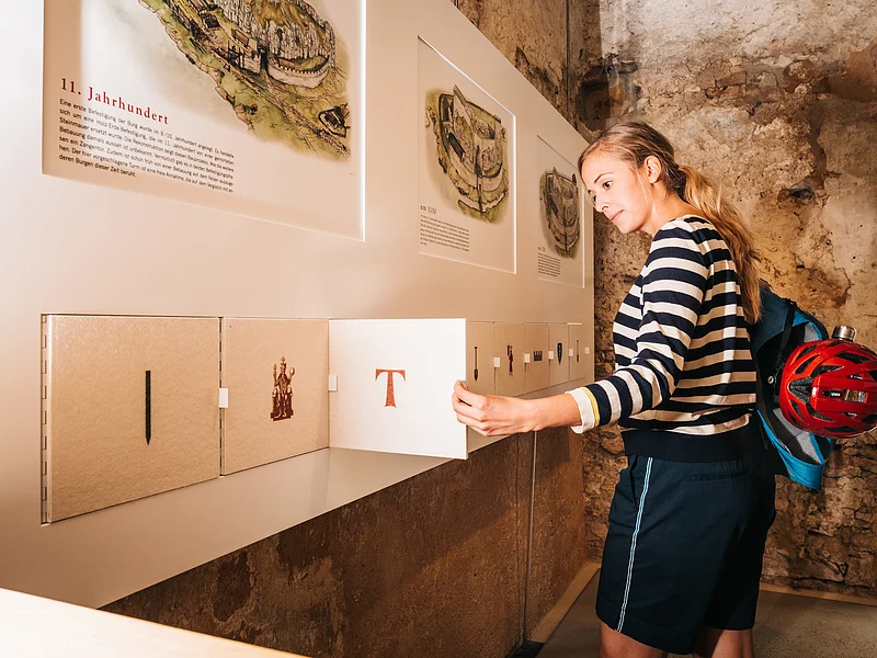 Altmühlzentrum Dollnstein Frau in gestreiftem Pullover öffnet Klappe an Ausstellungstafel mit historischen Texten und Bildern.